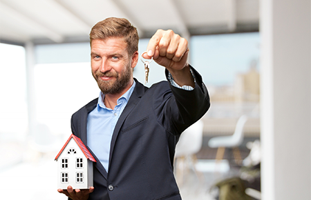 Businessman holding keys and a model house representing 100% financing